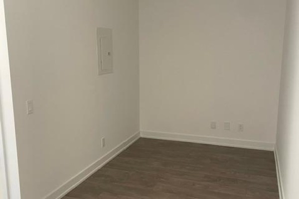 Empty room with white walls, dark hardwood floors, and a visible electrical panel on the wall. - 3815 - 108 Peter Street, Toronto