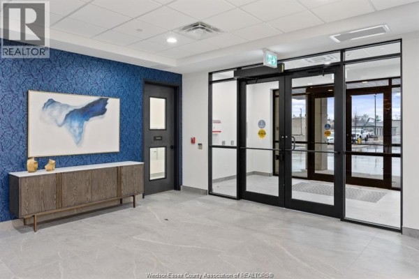Building lobby with blue textured wallpaper, gray floor, and entryway doors. - 3817 Howard Avenue Unit# 109, Windsor