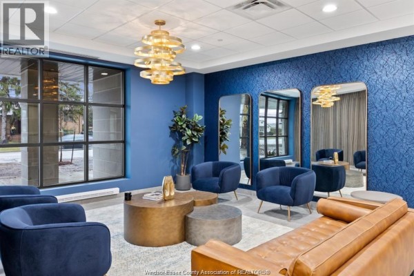 Apartment building lounge area with blue chairs, mirrors, and brown couch. - 3817 Howard Avenue Unit# 109, Windsor