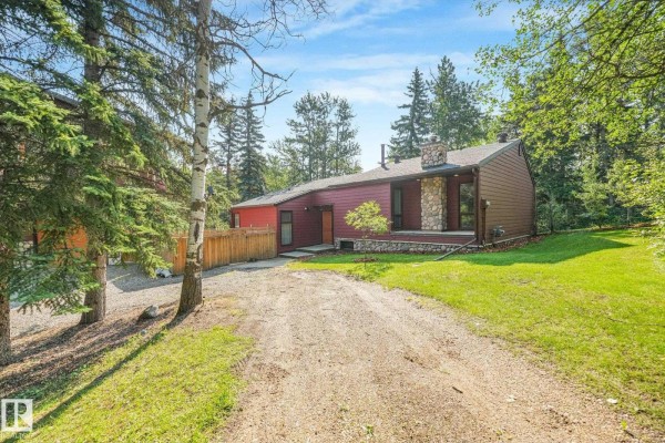 Front view of a red house with stone accents and a gravel driveway. - #382 51112 Rge Road 222, Rural Strathcona County