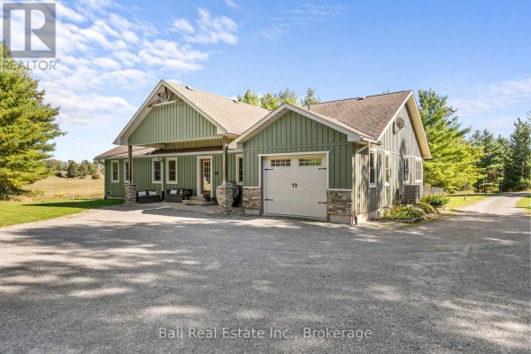 Side exterior of the green bungalow with a garage door and covered entrance. - 382 Lakehurst Circle Road, Trent Lakes