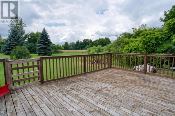 Wooden deck with railings and a gate overlooking a grassy area. - 3826 Big Rideau Lake Road, Rideau Lakes