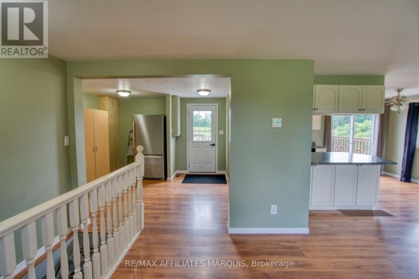 Interior view showing a staircase, kitchen, and hallway with a back door. - 3826 Big Rideau Lake Road, Rideau Lakes