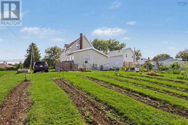 Rear view of the house showing the yard with garden beds and a parked vehicle. - 383 Kings Road, Dominion
