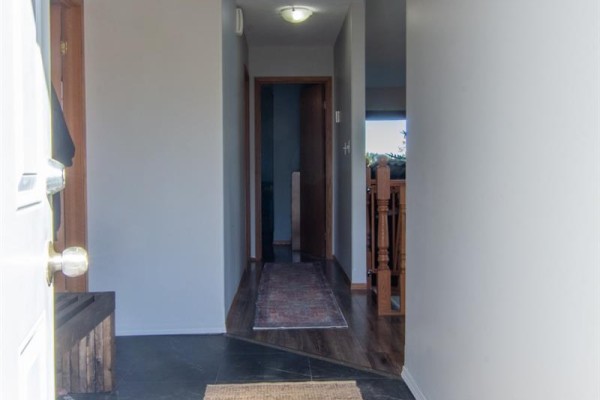 Interior hallway with a wooden door and view into living room with fireplace. - 3830 First Point Beach Drive, Wakaw Lake
