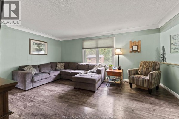 Living room with large sectional sofa, armchair, and paneled green walls. - 3831 Kathleen, Windsor