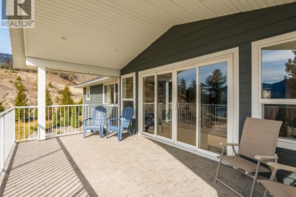 Stone patio with a fire pit overlooks a river valley with distant mountains. - 3835 5th Avenue, Castlegar