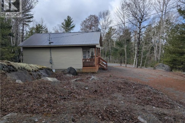 Winter view of a clearing with snow, firewood stacked, a storage shed, and surrounded by pine trees. - 3837 Route 122, Fosterville