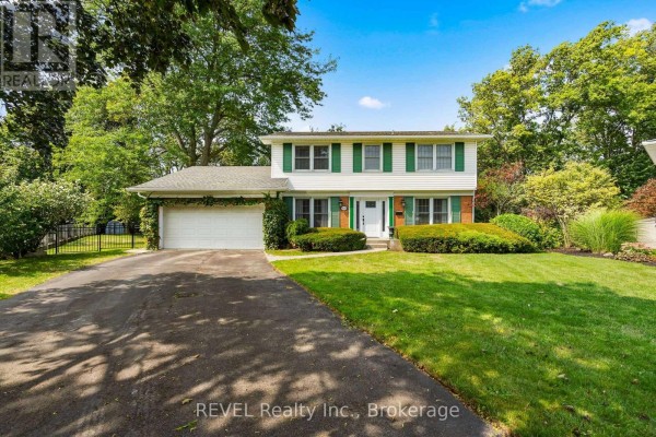 Front exterior view of a two-story white house with green shutters, attached garage, and manicured lawn. - 3839 Potter Heights, Niagara Falls