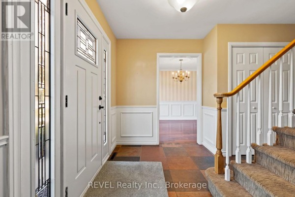 Interior entryway with tiled floor, wainscoting, and carpeted staircase leading upstairs. - 3839 Potter Heights, Niagara Falls