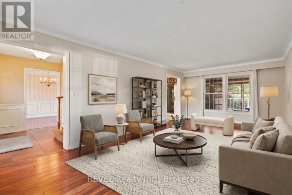 Living room with wood floors, beige carpet, furniture, and view into hallway. - 3839 Potter Heights, Niagara Falls