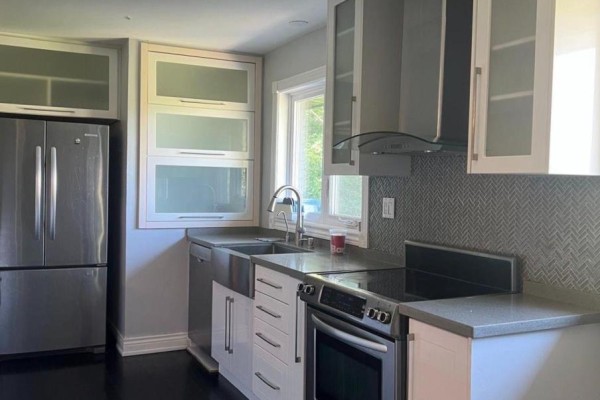 Modern kitchen with stainless steel appliances, grey backsplash, and white cabinets. - 384 Ashbury Road, Oakville