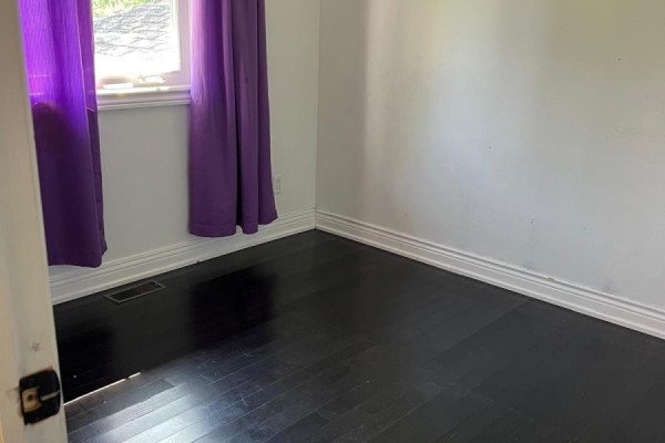 Empty bedroom with dark hardwood floors and bright purple curtains. - 384 Ashbury Road, Oakville