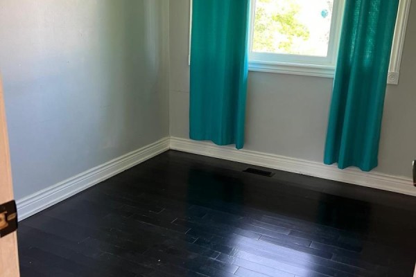 Empty bedroom with dark hardwood floors and bright teal curtains. - 384 Ashbury Road, Oakville