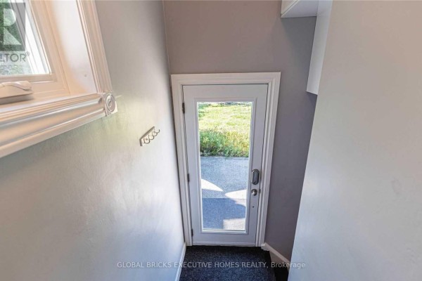 View down a hallway to a glass door leading outside. - 384 Ashbury Road, Oakville
