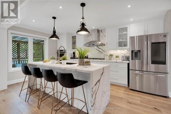 Kitchen island with seating for four faces a gas range and stainless steel refrigerator. - 3840 Althorpe Circle, Mississauga