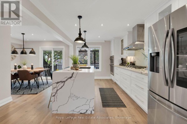 View of kitchen island, dining area with live-edge table, and living room with fireplace. - 3840 Althorpe Circle, Mississauga