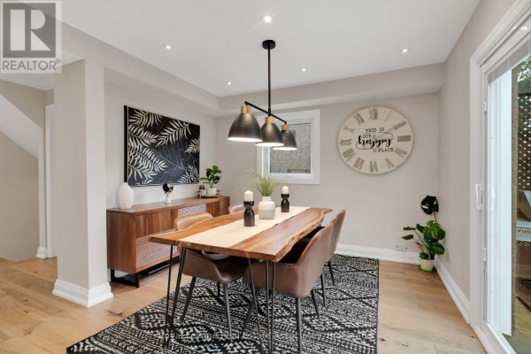 Dining room with live-edge table, dark upholstered chairs, and large wall clock. - 3840 Althorpe Circle, Mississauga