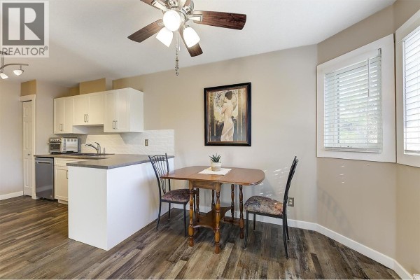 Dining area adjacent to kitchen with a small wooden table, two chairs, and a window. - 3842 Gordon Drive Unit# 216, Kelowna