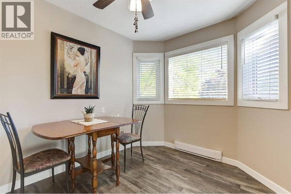 Corner dining area with two chairs, a table, and large windows with blinds. - 3842 Gordon Drive Unit# 216, Kelowna