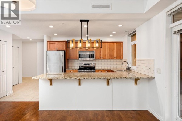 Dining area with wooden table, chairs, and open kitchen layout. - 3843 Brown Road Unit# 2101, West Kelowna