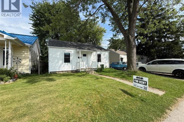 Side view of a white house with a lawn and large tree. - 3847 Matchett Road, Windsor