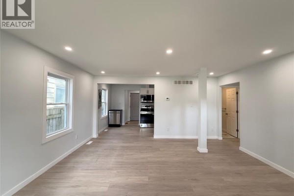 Open concept living area with light grey walls and wood-look flooring. - 3847 Matchett Road, Windsor