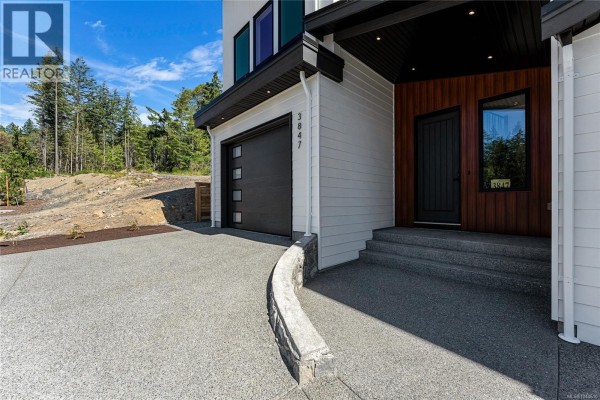 Seating area with orange booths, pendant lights, and a view into the kitchen. - 3847 Olympian Way, Colwood