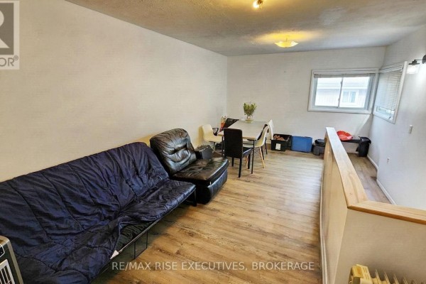 Living area with a blue futon, black leather armchair, and dining table with chairs. - 385 Alfred Street, Kingston