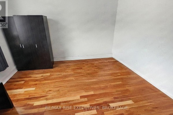 Empty bedroom with natural wood hardwood floors and a dark brown wardrobe. - 385 Alfred Street, Kingston