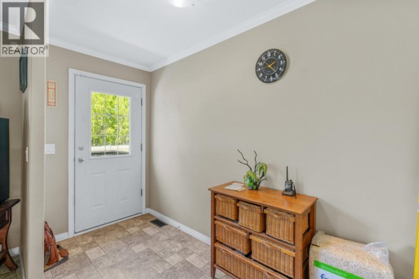 Entranceway inside a mobile home with a glass-paned door, beige walls, tile flooring, and a wooden cabinet. - 385 Colgrove Road, Hixon