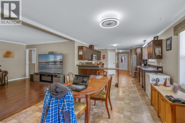 Open-concept living, dining, and kitchen area in a mobile home with dark wood cabinets and laminate flooring. - 385 Colgrove Road, Hixon