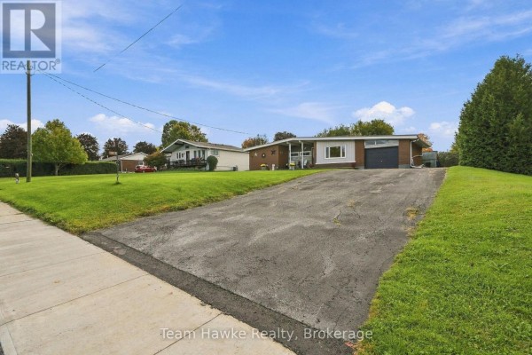 Paved driveway leading to a single-story house with a garage and front lawn. - 385 Lafontaine Road W, Tiny