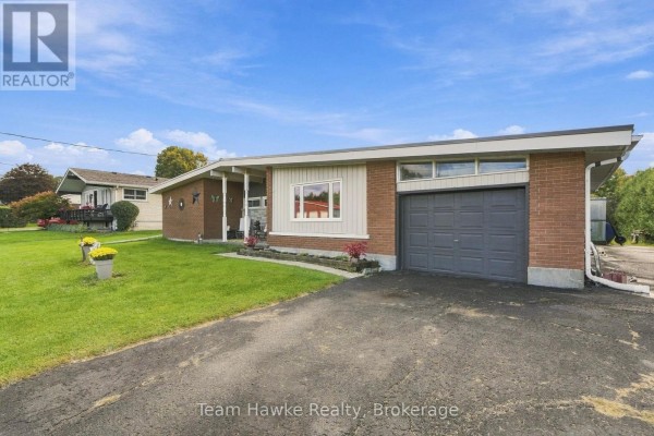 Side view of a brick ranch house showing the driveway and garage entrance. - 385 Lafontaine Road W, Tiny