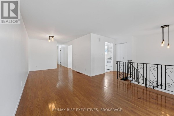 Open concept living and dining area with hardwood floors, white walls, and a view into a hallway and kitchen area. - 385 Melanie Avenue, Kingston