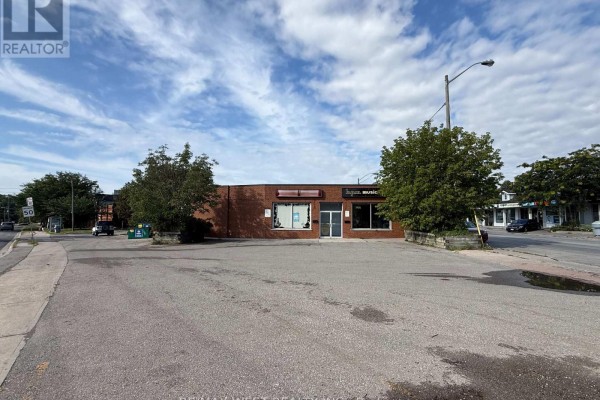 Exterior view of a single-story commercial building with a brick facade and parking lot. - 385 Old Kingston Road, Toronto