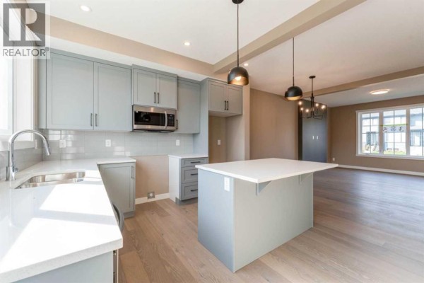 Light grey kitchen with white quartz counters, stainless steel appliances, and island. - 385 Waterford Boulevard, Chestermere