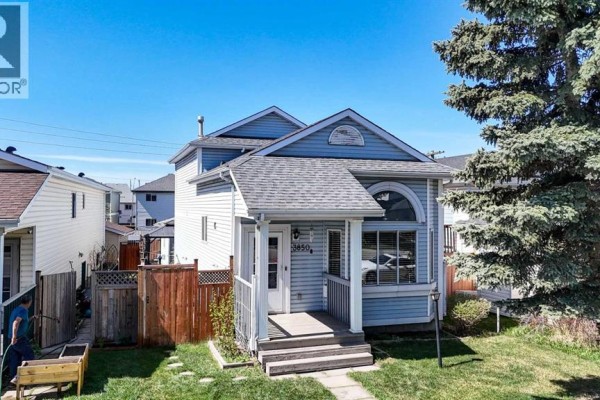 Aerial view of the front exterior of a light blue two-story house with a covered porch. - 3850 Catalina Boulevard Ne, Calgary