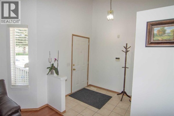 Entranceway with beige tile flooring, white walls, and a white door. - 3850 Catalina Boulevard Ne, Calgary
