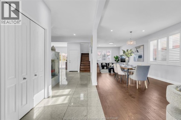 Interior view of dining area with large windows, tile flooring, and wooden staircase. - 3852 Concord Court, Windsor