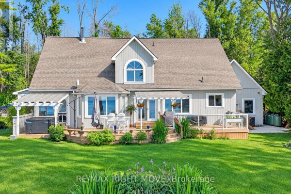 Back exterior of a two-story home with a deck, hot tub, and water view. - 3852 Muley Point Road, Ramara