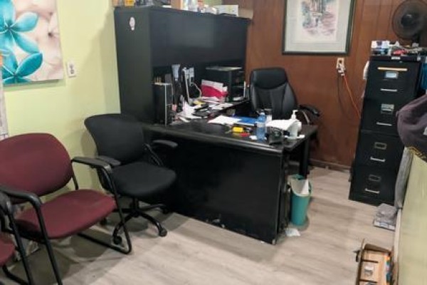 Office interior with a black desk, two chairs, a filing cabinet, and artwork on the wall. - 3857 Wyandotte Street East, Windsor