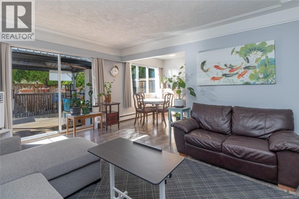 Living room with grey sofa, dark leather sofa, dining area, and sliding glass door to deck. - 386 Burnside Rd W, Saanich