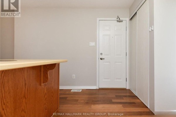Interior view of a hallway with hardwood floors, a white door, and a wooden island counter. - 386 Crownridge Drive, Ottawa