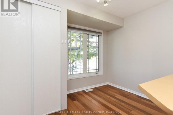 Interior view of a room with hardwood floors, a large window, and a white sliding door closet. - 386 Crownridge Drive, Ottawa