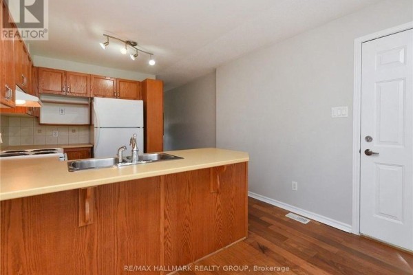 View of a kitchen with wooden cabinets, a stainless steel sink, and a light-colored countertop. - 386 Crownridge Drive, Ottawa