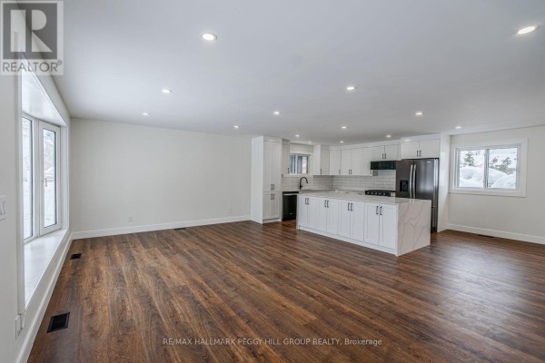 Kitchen with white cabinets, large island, stainless steel appliances, and ample natural light. - 386 Peter Street N, Orillia