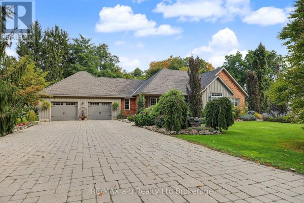 Front exterior of a sprawling ranch home with a wide paver driveway leading to a three-car garage. - 386087 Second Road, Norwich