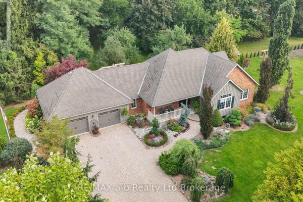Aerial view of a spacious brick ranch home surrounded by mature trees and lush green lawn. - 386087 Second Road, Norwich