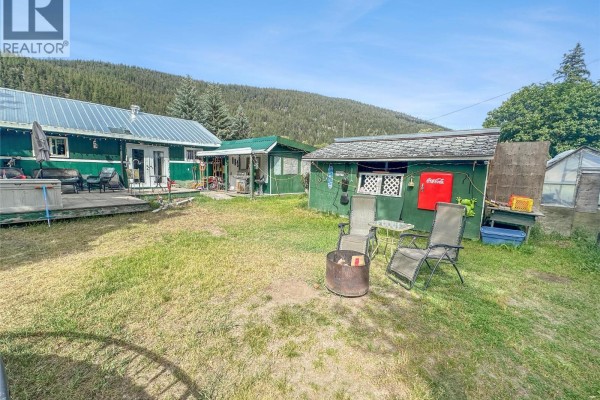 Backyard with a green shed, a fire pit, lawn chairs, and a greenhouse. - 387 Parrish Avenue, Coalmont Tulameen